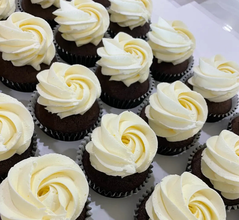 Chocolate cupcakes with white frosting on a white plate